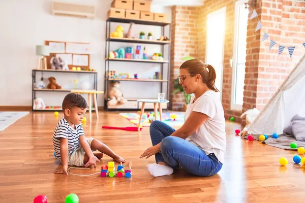 Güzel öğretmen ve küçük çocuk anaokulunda trenle oynuyor.