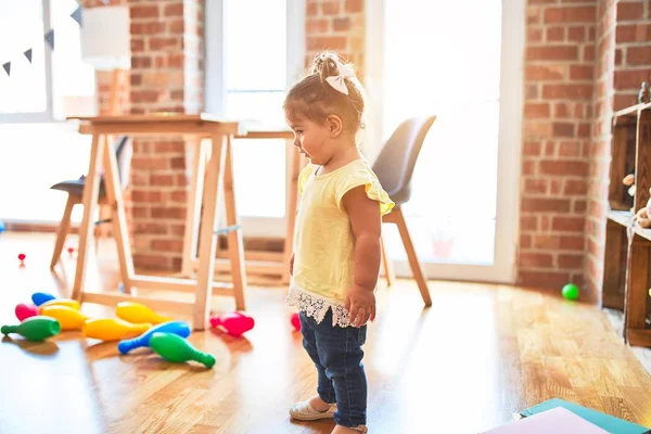 Anaokulunda bir sürü oyuncağın etrafında duran güzel çocuk.