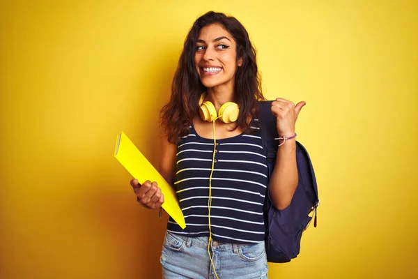 Studentin Mit Bakcpack Notizbuch Kopfhörer Über Isoliertem Gelbem Hintergrund Zeigt — Stockfoto