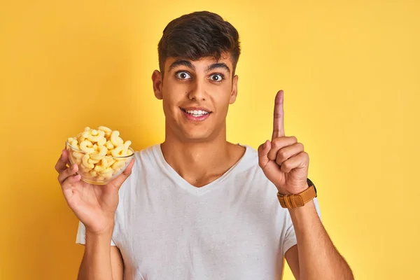 Young Indian Man Holding Bowl Extruded Corn Standing Isolated Yellow — Stock Photo, Image