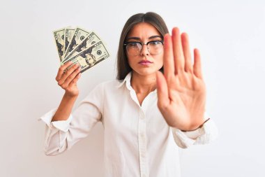Gözlük takan güzel bir iş kadını. İzole edilmiş beyaz arka planda dolar taşıyor. Açık elle dur işareti yapıyor.