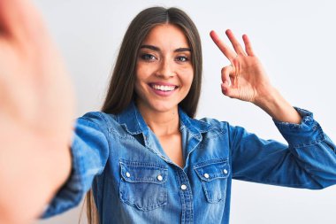 Kot gömlek giyen güzel bir kadın, izole edilmiş beyaz arka planda el ve parmaklarıyla 