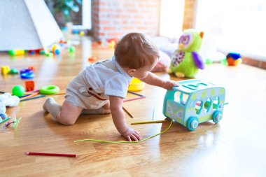 Anaokulunda bir sürü oyuncakla oynayan sevimli bir çocuk.