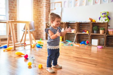 Güzel çocuk, kreşte ayakta alkışlıyor ve gülümsüyor.