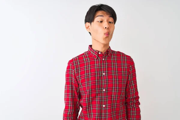 狂気とコミカルなジェスチャーで魚の顔を作る隔離された白い背景の上に立ってカジュアルな赤いシャツを着て若い中国人男性 面白い表現 — ストック写真