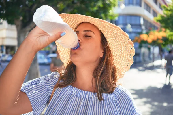 夏の晴れた日に新鮮な水を飲んで街の通りを歩く幸せな笑顔の若い美しい女性 — ストック写真