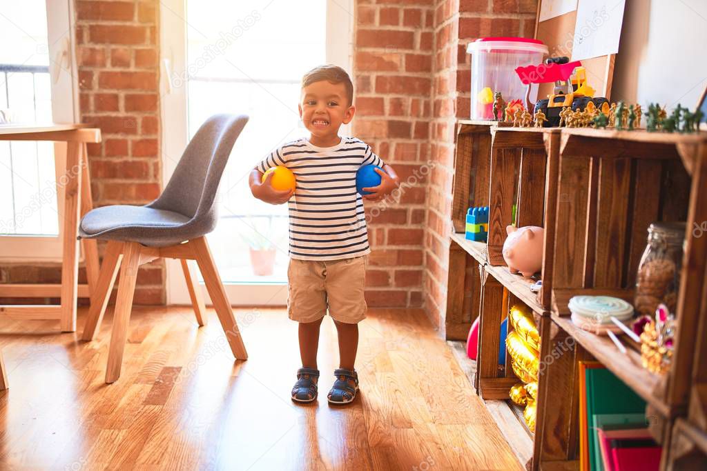 Beautiful toddler boy playing with colored small balls at kindergarten