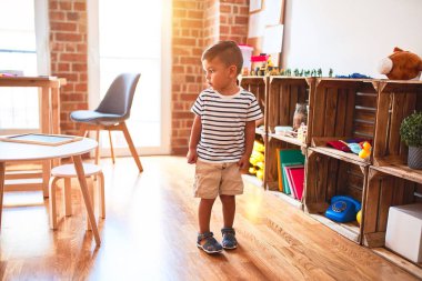 Anaokulunda bir sürü oyuncakla bekleyen güzel bir çocuk.
