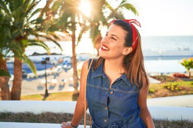 Genç, güzel bir kadın mutlu bir şekilde gülümsüyor. Güneşli bir yaz gününde Tenerife, Puerto de la Cruz sokaklarında yürüyor.