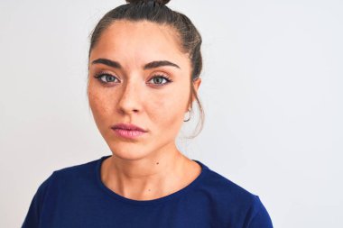 Mavi günlük tişört giyen genç ve güzel bir kadın izole edilmiş beyaz arka planda duruyor. Akıllı bir yüz ifadesiyle ciddi ciddi düşünüyor.