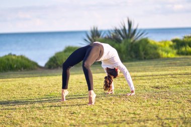 Genç yakışıklı sporcu yoga yapıyor. Koç parkta direksiyon pozu veriyor.
