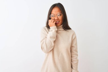 Young chinese woman wearing turtleneck sweater and glasses over isolated white background looking stressed and nervous with hands on mouth biting nails. Anxiety problem.