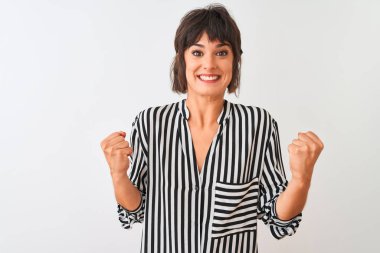 İzole edilmiş beyaz arka plan üzerinde duran çizgili tişört giyen genç ve güzel bir kadın kollarını kaldırarak ve açık gözlerle başarıyı kutluyor. Kazanan konsept.