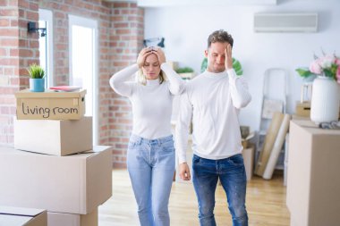 Genç ve güzel bir çift yeni evlerinde karton kutuların etrafında dikilip acı ve migren yüzünden çaresiz ve stresli bir şekilde acı çekiyorlar. Ellerini başının üstüne koy..