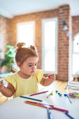 Anaokulunun masasında çikolata renkli toplarla oynayan güzel çocuk.