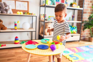 Anaokulunda plastik tabaklar, meyveler ve sebzelerle oynayan güzel bir çocuk.