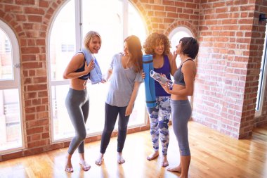 Mutlu gülümseyen genç ve güzel bir spor kadını grubu. Beden dersinden sonra yüzünde gülümsemeyle ayakta dikilip konuşmak.
