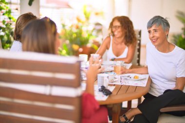 Genç ve güzel bir kız mutlu ve kendinden emin bir şekilde terasta oturmuş bir fincan kahve içiyor.