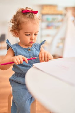 Renkli oyun odasında beyaz güzel bir bebek oyuncaklarla oynuyor. Anaokulunda renkli kalemlerle mutlu ve eğlenceli çizimler..