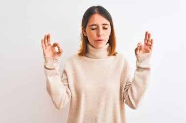 Kış balıkçı yaka kazak giyen güzel kızıl kadın izole arka planda rahatla ve parmaklarıyla meditasyon hareketi yaparken gözleri kapalı gülümse. Yoga konsepti.