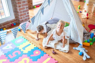 Anaokulundaki bir sürü oyuncağın etrafında battaniyenin üstünde oynayan güzel bebekler.