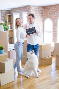 Karton kutuların etrafındaki yeni evlerinde ellerinde karatahtayla bekleyen genç ve güzel bir çift.