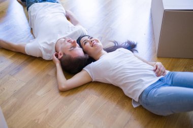 Genç güzel çift karton kutular etrafında yeni evde yatarken