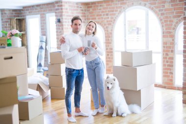 Köpekleri olan genç ve güzel bir çift yeni evlerinde karton kutuların etrafında kahve içiyorlar.