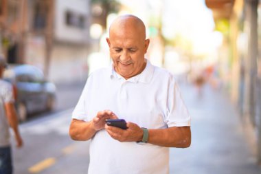 Kıdemli yakışıklı adam mutlu ve kendinden emin gülümsüyor. Yüzünde gülümsemeyle şehrin caddesinde akıllı telefon kullanarak dikiliyorsun.