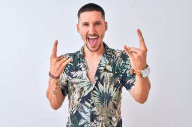 İzole edilmiş arka planda Hawaii tişörtü giyen genç yakışıklı adam elleri havada rock sembolü yaparken çılgın bir ifadeyle bağırıyor. Müzik yıldızı. Ağır konsept.