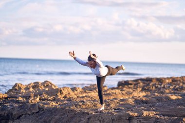 Genç yakışıklı sporcu yoga yapıyor. Koç kumsalda savaşçı pozu veriyor.