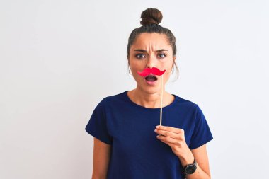 Genç, güzel bir kadın, kıç partisi bıyığını izole edilmiş beyaz arka planda tutuyor. Şaşırmış bir yüzle korkmuş, korku ifadesinden korkmuş ve heyecanlanmış.