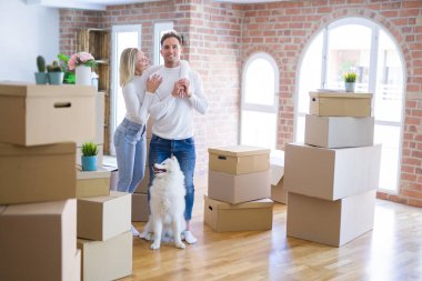 Karton kutular etrafında yeni evde duran köpek ile genç güzel çift