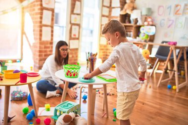 Güzel öğretmen ve bebek anaokulunda bir sürü oyuncakla oynuyorlar.