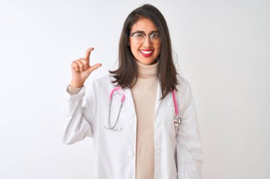 İzole edilmiş beyaz arka plan üzerinde pembe steteskop ve ceket giyen Çinli doktor kadın gülümsüyor ve el hareketleriyle küçük boy işareti yapıyor ve kameraya bakıyor. Ölçü kavramı.