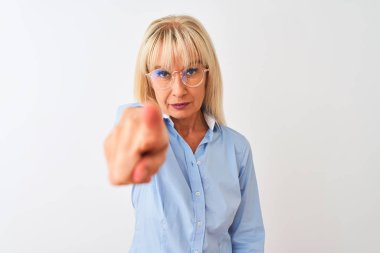 Gözlüklü ve gömlekli orta yaşlı bir iş kadını izole edilmiş beyaz arka planda dikiliyor. Kamerayı işaret ediyor. Ve sen, el işareti, ön taraftan pozitif ve kendinden emin bir hareket.