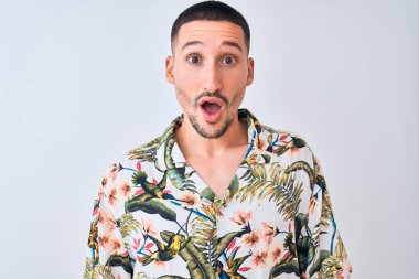 Hawaii yazlığı tişörtü giyen genç yakışıklı arka planda korku, korku ve heyecan dolu bir yüz ifadesiyle korkmuş ve şok olmuştu..