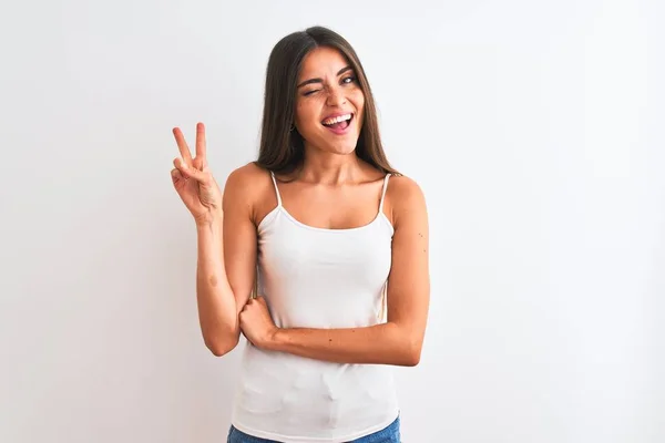 カジュアルなTシャツを着た若い美人女性が 勝利のサインをしているカメラで幸せそうな顔で微笑む孤立した白い背景の上に立っている ナンバー2 — ストック写真