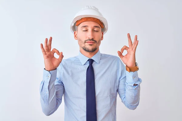 年轻的商人戴着承包商的安全帽 戴着孤立的背景 带着微笑 闭上眼睛 用手指做冥想动作 瑜伽概念 — 图库照片