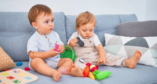 Gyönyörű Kisbabák Ülnek Kanapén Otthon Játszanak Játékaikkal — Stock Fotó