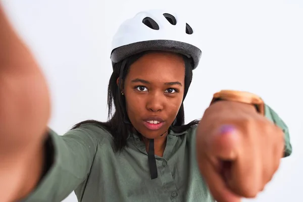 Young african american woman wearing bike helmet taking a selfie over isolated background pointing with finger to the camera and to you, hand sign, positive and confident gesture from the front
