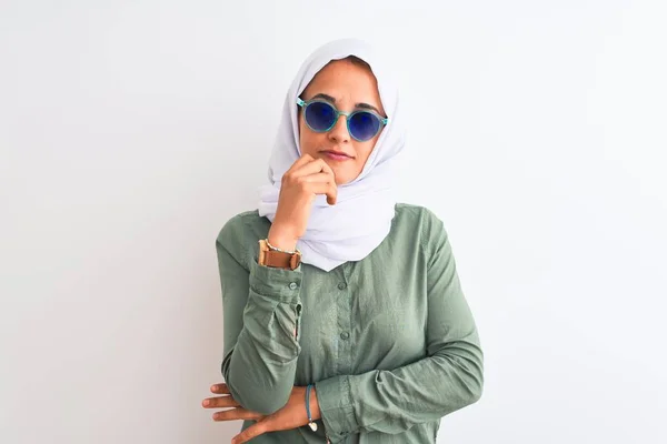 ヒジャーブと夏のサングラスを身に着けている若いアラブの女性は 顎の質問について考えて手で隔離された背景に 集中的な表現 思慮深い顔で微笑んだ 疑いの概念 — ストック写真