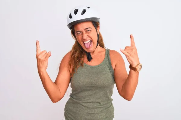 中年の成熟したサイクリストの女性は手を上げてロックシンボルをやって狂気の表情で叫んで隔離された背景に安全ヘルメットを身に着けています 音楽スター 重い音楽の概念 — ストック写真