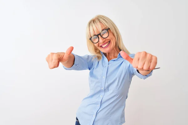 Middle age businesswoman wearing elegant shirt and glasses over isolated white background approving doing positive gesture with hand, thumbs up smiling and happy for success. Winner gesture.