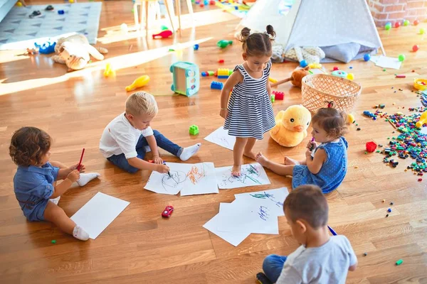 幼儿园里 一群可爱的幼儿坐在地板上 用纸笔画着许多玩具 — 图库照片