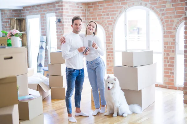Köpekleri olan genç ve güzel bir çift yeni evlerinde karton kutuların etrafında kahve içiyorlar.