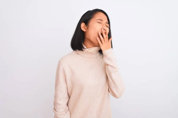 年轻的中国女人穿着高领毛衣站在孤立的白色背景上 厌烦地打呵欠 双手捂着疲惫的嘴 烦躁不安和困倦 — 图库照片