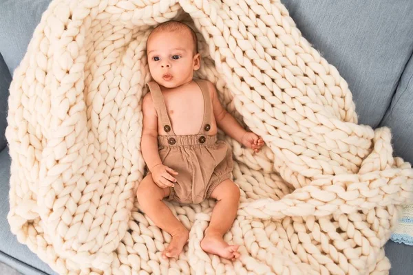 Adorable baby lying down over blanket on the sofa at home. Newborn relaxing and resting comfortable