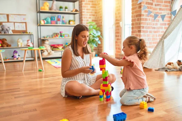 Schöne Lehrerin Und Blondes Kleinkind Bauen Turm Aus Plastikklötzen Kindergarten — Stockfoto