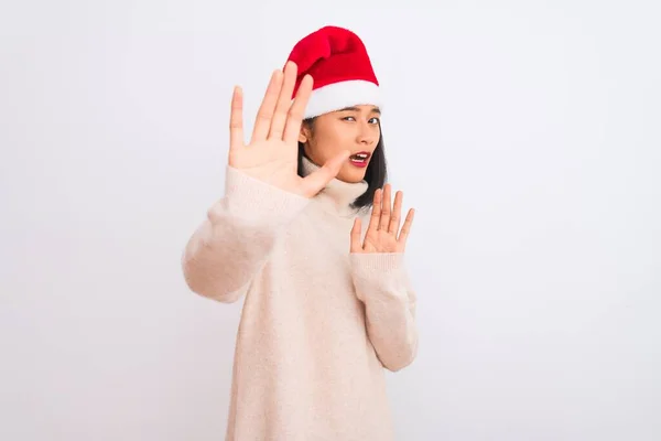 年轻美丽的中国女人 戴着圣诞礼帽 披着孤立的白色背景 恐惧而又害怕 用手拿着恐惧的表情 停止了举手表决 震惊地大叫 恐慌的概念 — 图库照片